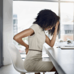 A woman holding her back, indicating pain.