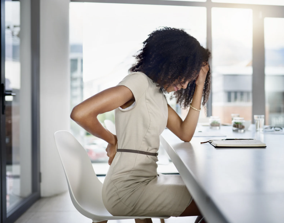 A woman holding her back, indicating pain.