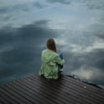 A woman sitting in front of a lake.