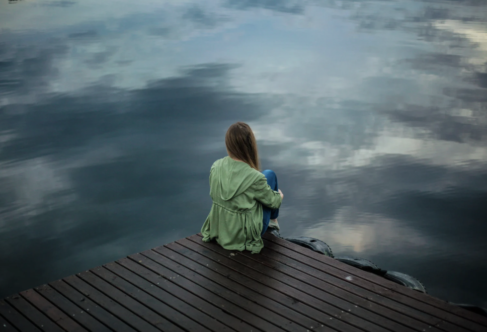 A woman sitting in front of a lake.