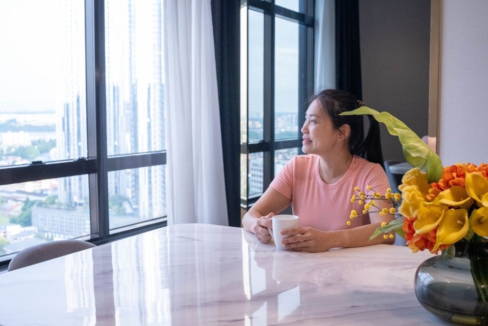 2. A woman at a table, enjoying a coffee cup, with a calm demeanor and a cozy atmosphere around her.