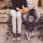 Carolina Dunes - Teen Dating Violence Prevention Month - Edited. Two youth sit outdoors holding hands with one another.